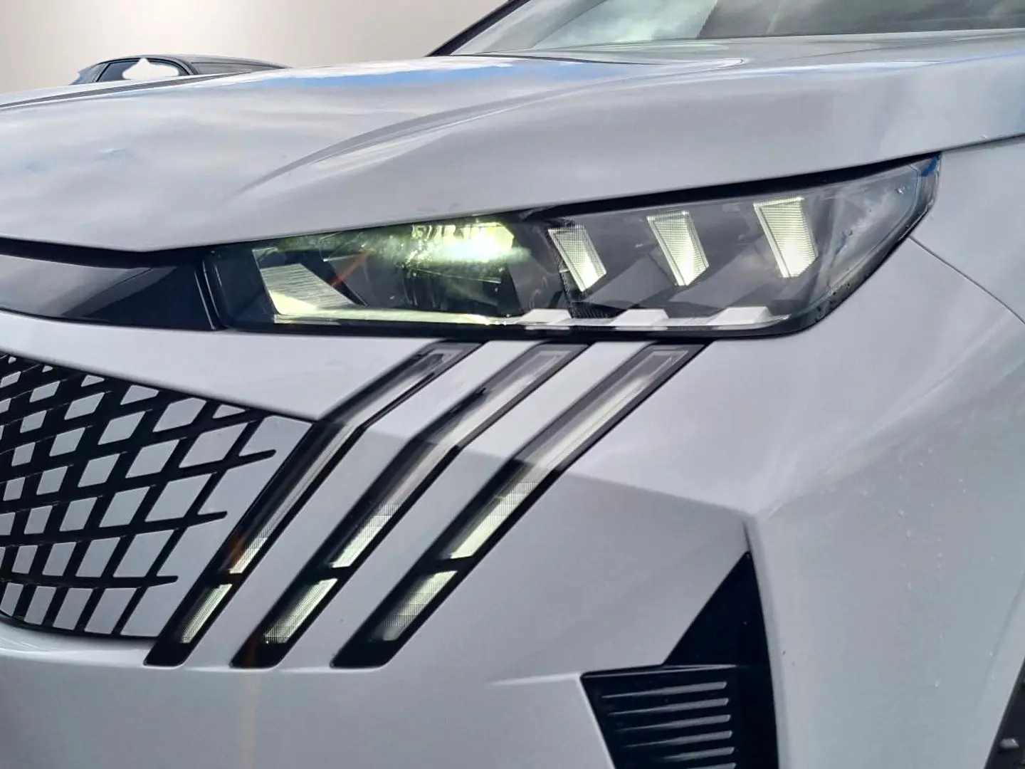 Gros plan sur le phare avant droit blanc du Peugeot 3008 1.2 hybrid 145 GT avec signature lumineuse en griffes LED.