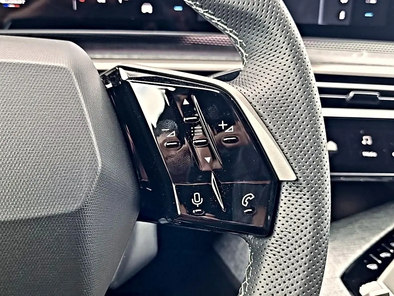 Gros plan sur les commandes multifonctions noires à gauche du volant cuir perforé du Peugeot 3008 blanc toit noir.