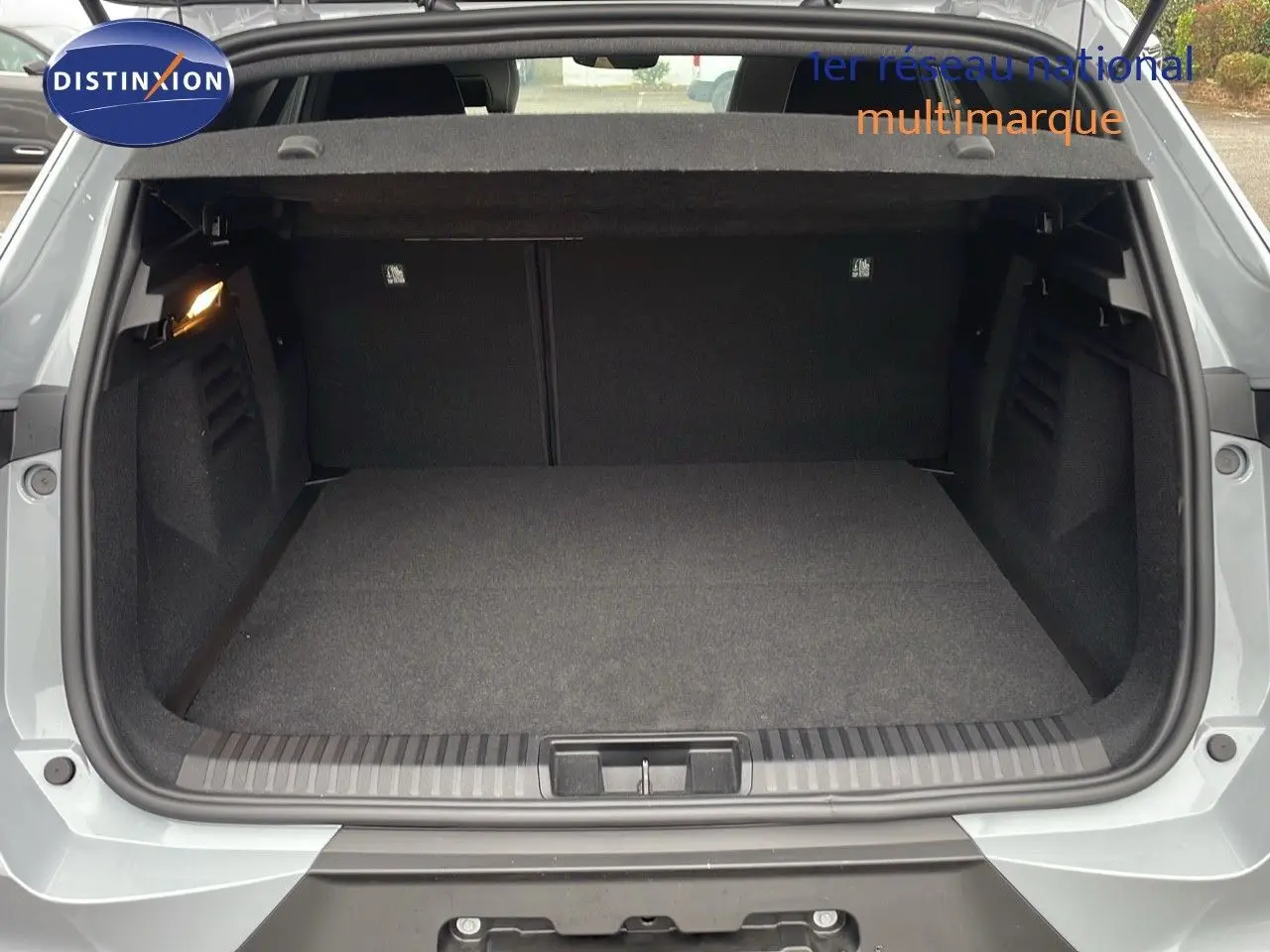 Coffre ouvert vu de l'arrière d'une Renault Symbioz gris Rafale Métal, intérieur spacieux et tapis noir.