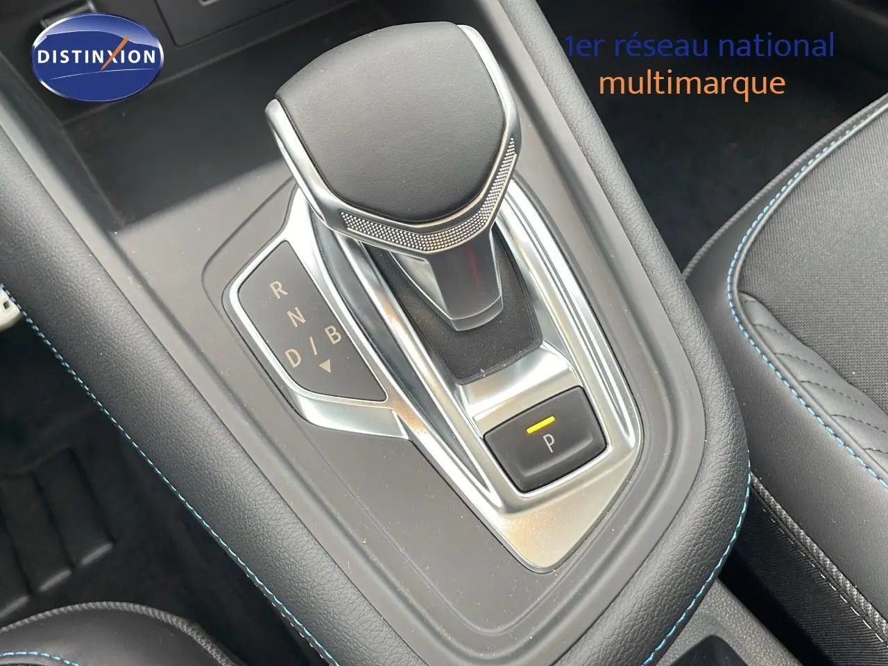 Le levier de vitesses automatique de la Renault Symbioz hybride, entouré de coutures bleues sur la console noire.