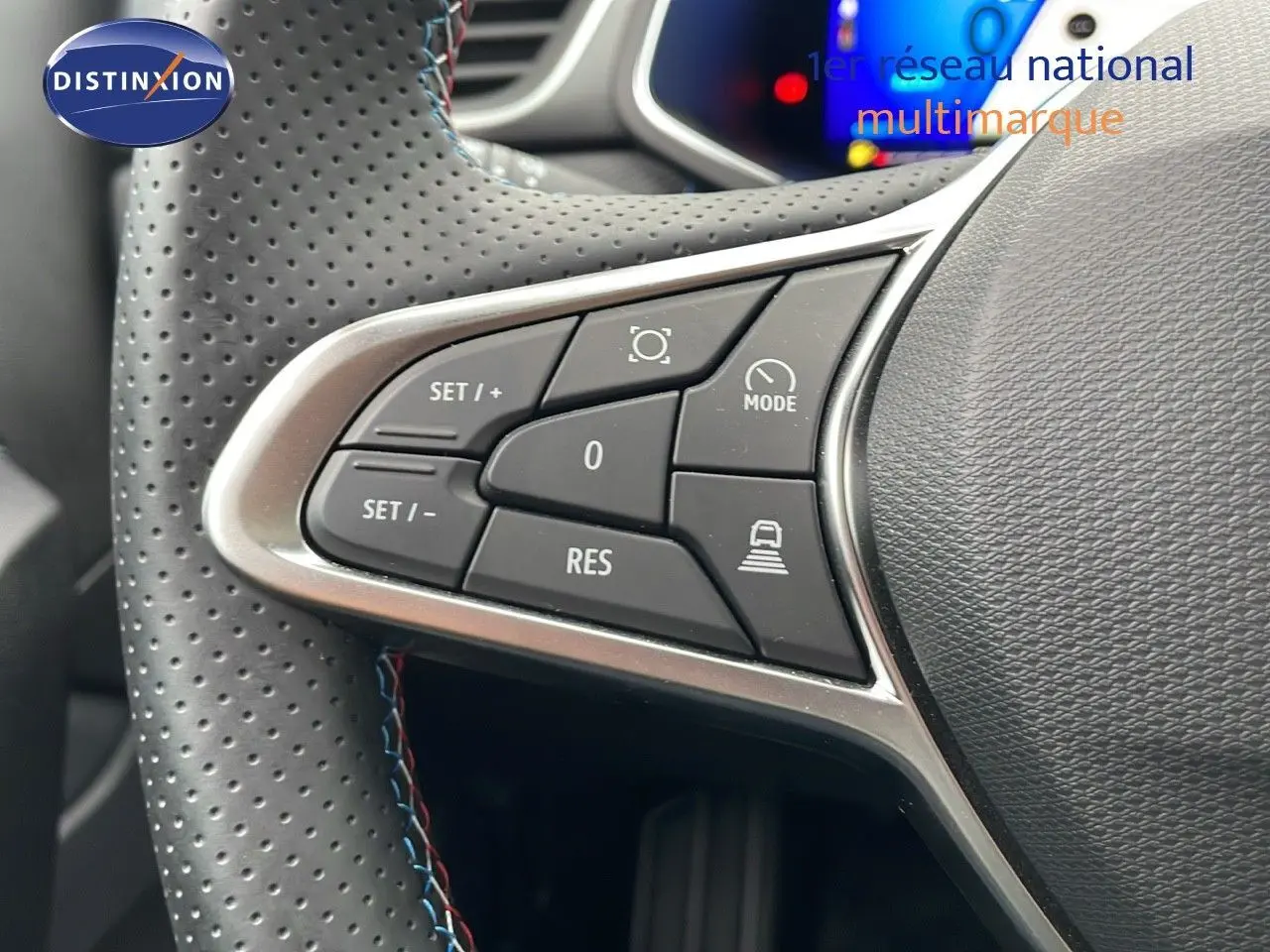 Gros plan sur les commandes du volant en cuir noir perforé de la Renault Symbioz gris Rafale, version hybride 2025.