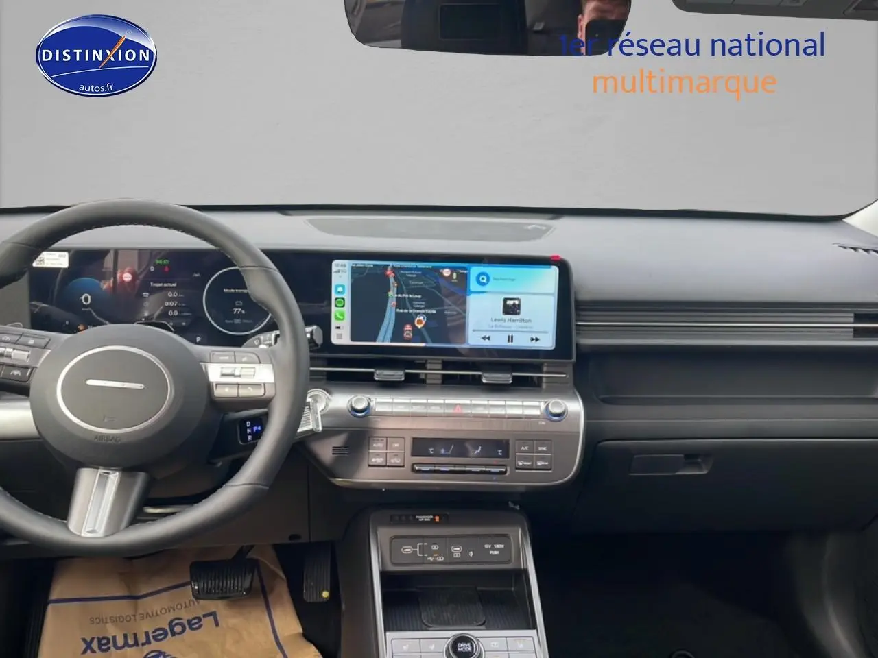 Vue intérieure du tableau de bord du Hyundai Kona 2025 avec écran tactile central affichant la navigation et le volant multifonction en cuir noir.