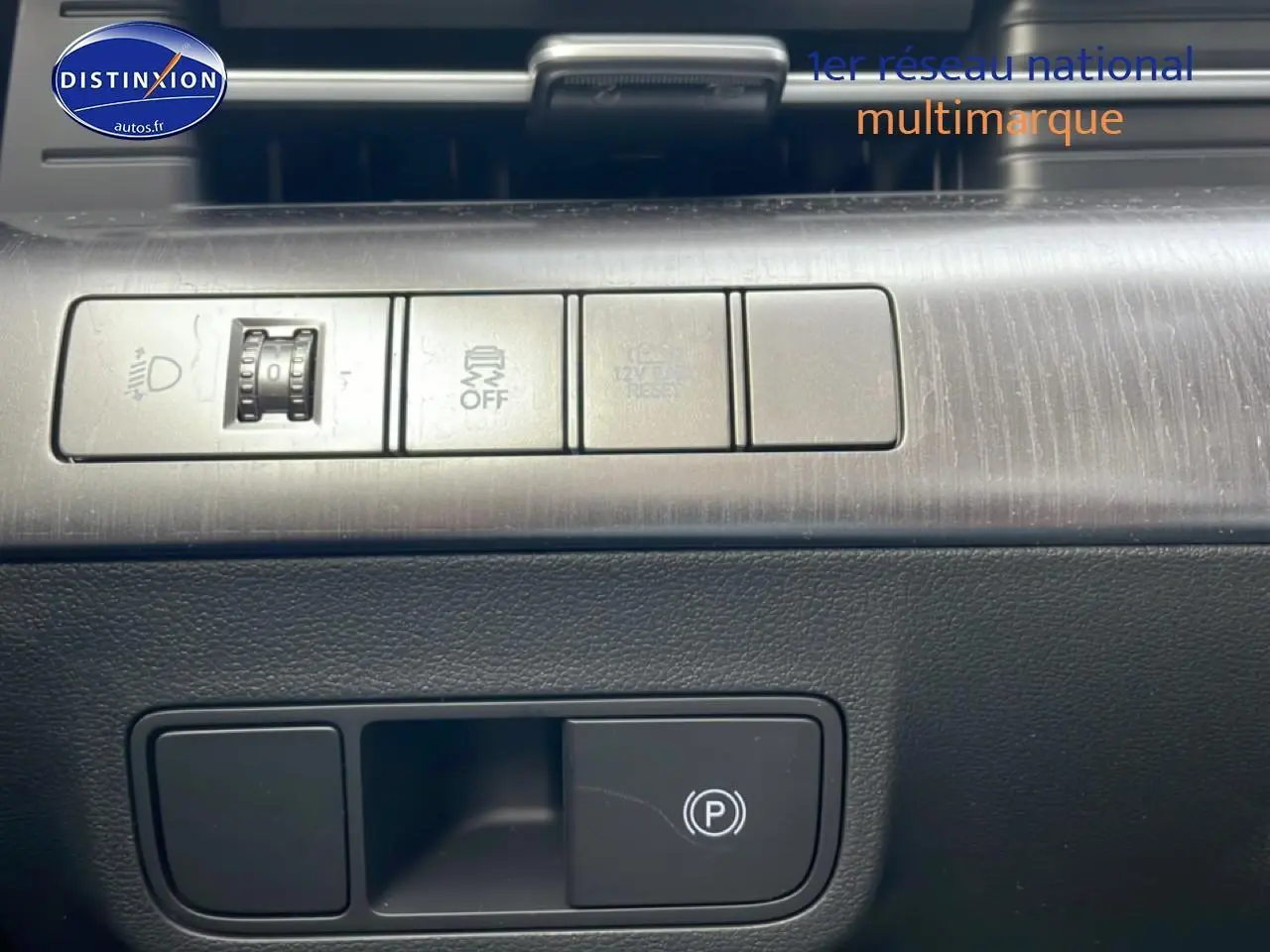 Gros plan sur les commandes intérieures du Hyundai Kona 2025, avec bouton frein à main électrique et réglage éclairage.