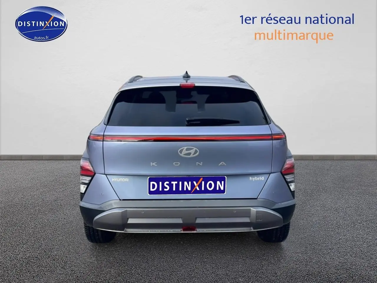 Vue arrière d'un Hyundai Kona bleu 2025 avec bande lumineuse LED et logo hybride visible sur le hayon.