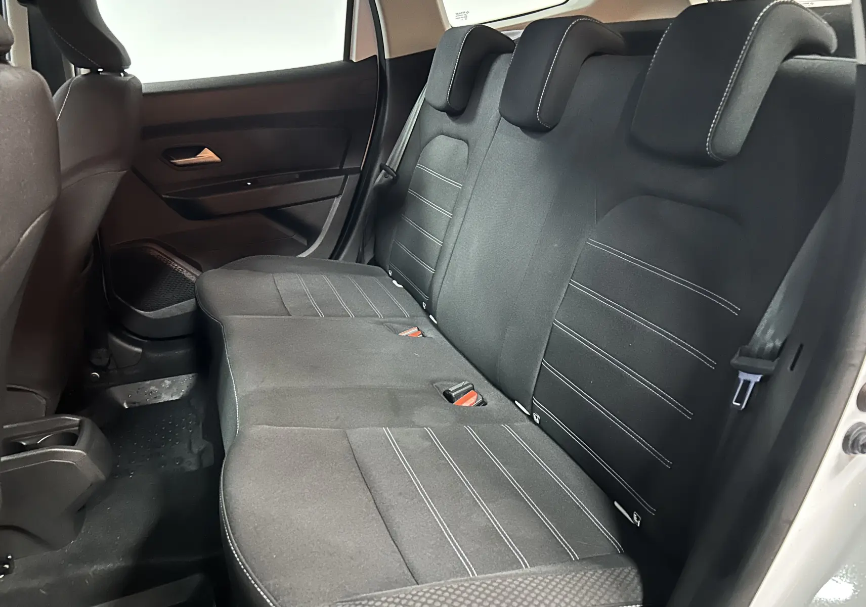 Vue intérieure côté droit des sièges arrière en tissu noir avec surpiqûres blanches du Dacia Duster blanc 2023.