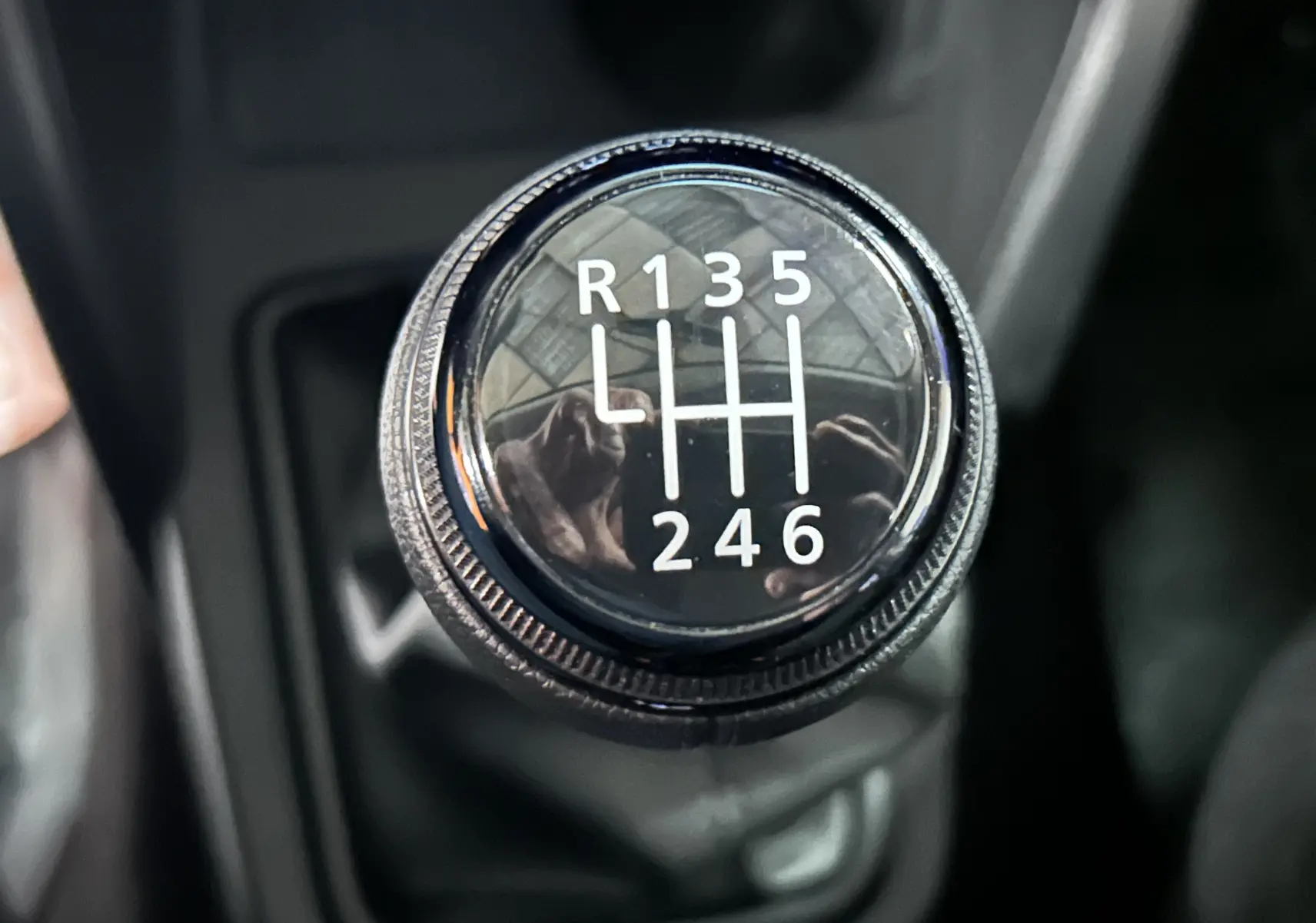 Gros plan sur le levier de vitesses manuel noir du Dacia Duster BluedCi 115, affichant les six rapports et la marche arrière.