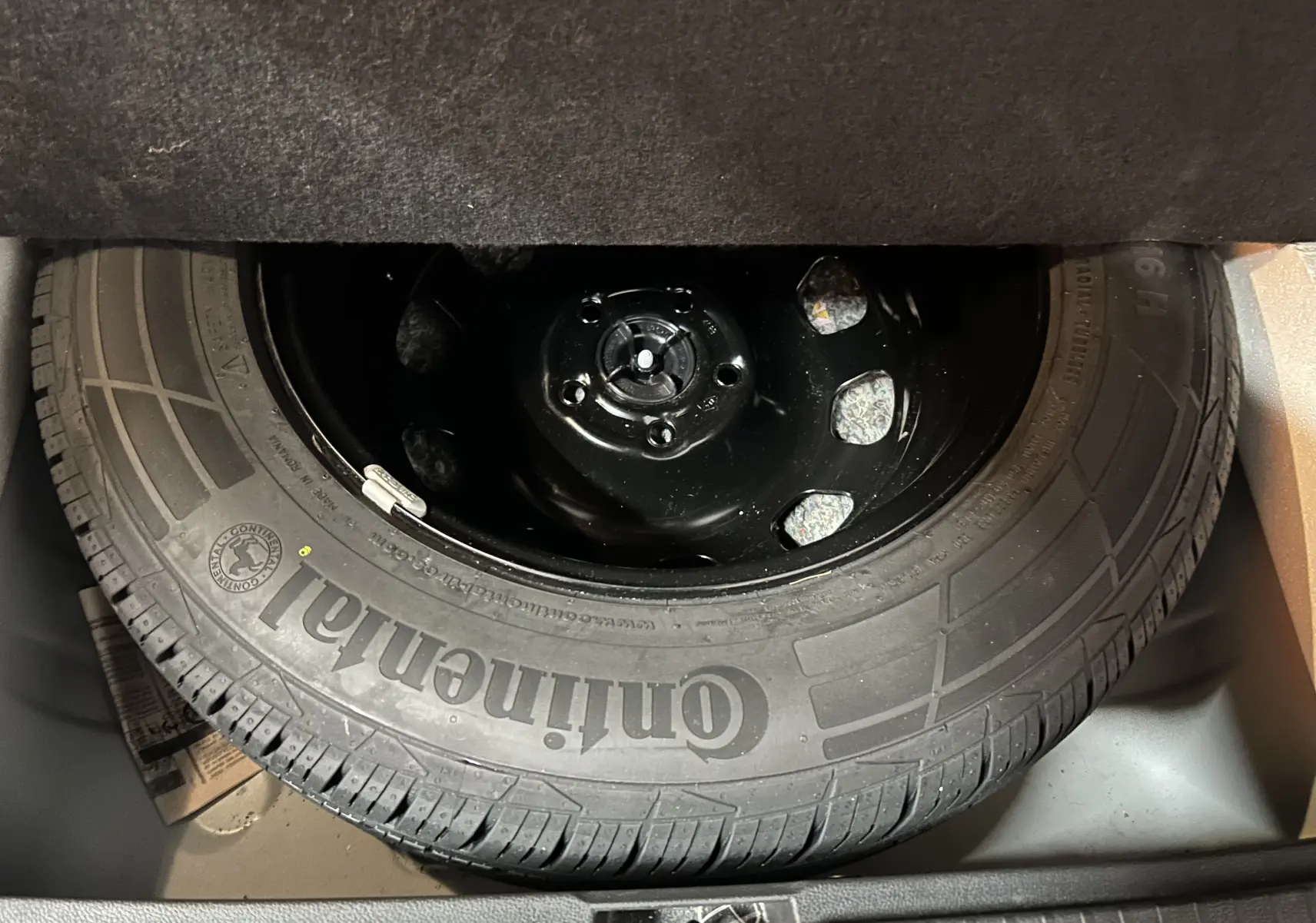 Gros plan sur la roue de secours Continental dans le coffre d’un Dacia Duster blanc 2023.