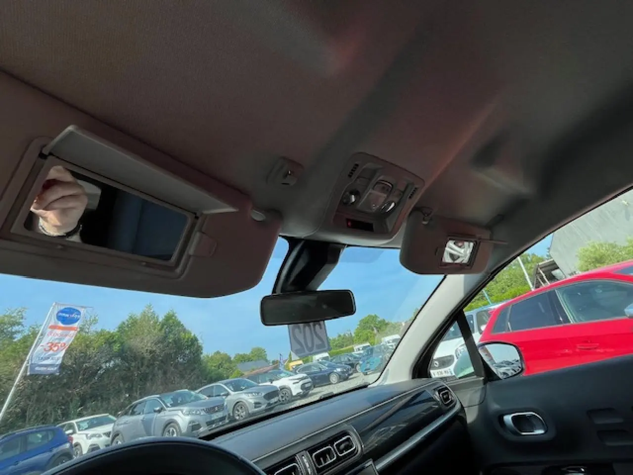 Vue intérieure avant droite du tableau de bord et pare-brise d'une Citroën C3 noire 2023 avec pare-soleil et rétroviseur central.