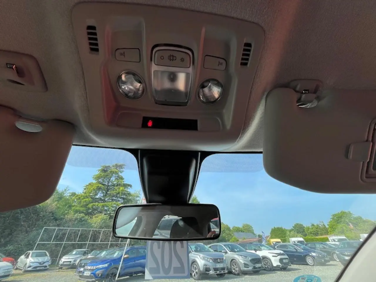 Vue intérieure avant du pare-brise et rétroviseur d’une Citroën C3 noire, avec ciel bleu en arrière-plan.