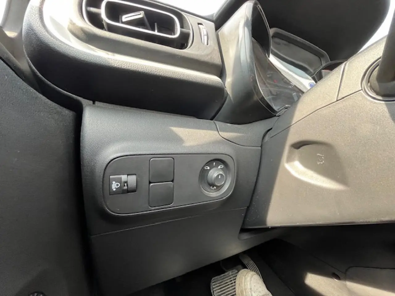 Vue intérieure côté gauche du tableau de bord noir de la Citroën C3 2023, avec commandes des rétroviseurs et éclairage.