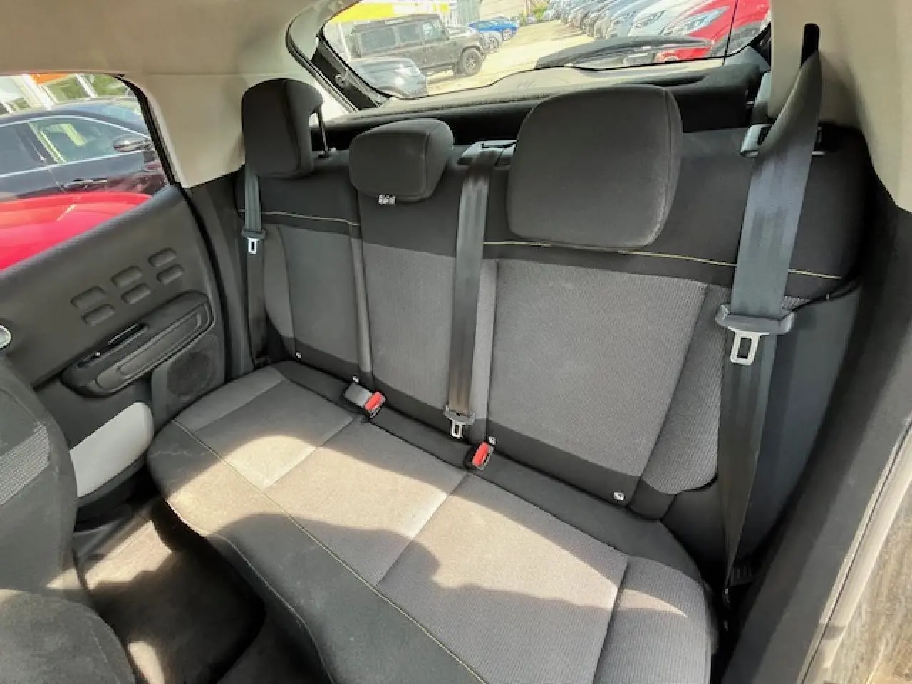 Banquette arrière en tissu gris et noir de la Citroën C3 2023, vue de côté droit avec ceintures de sécurité visibles.