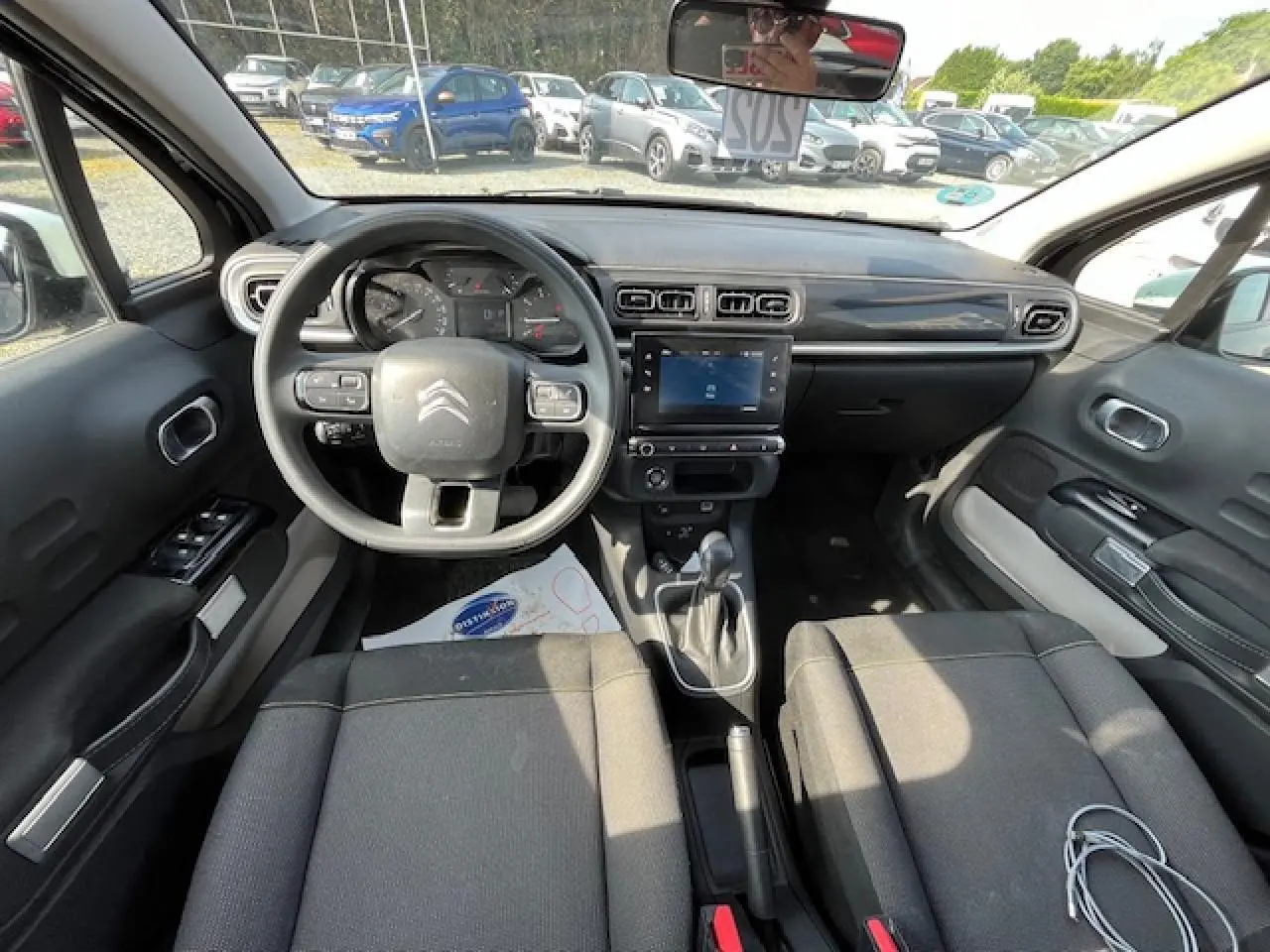 Vue intérieure avant de la Citroën C3 noire 2023, montrant le tableau de bord avec écran tactile et volant multifonction.
