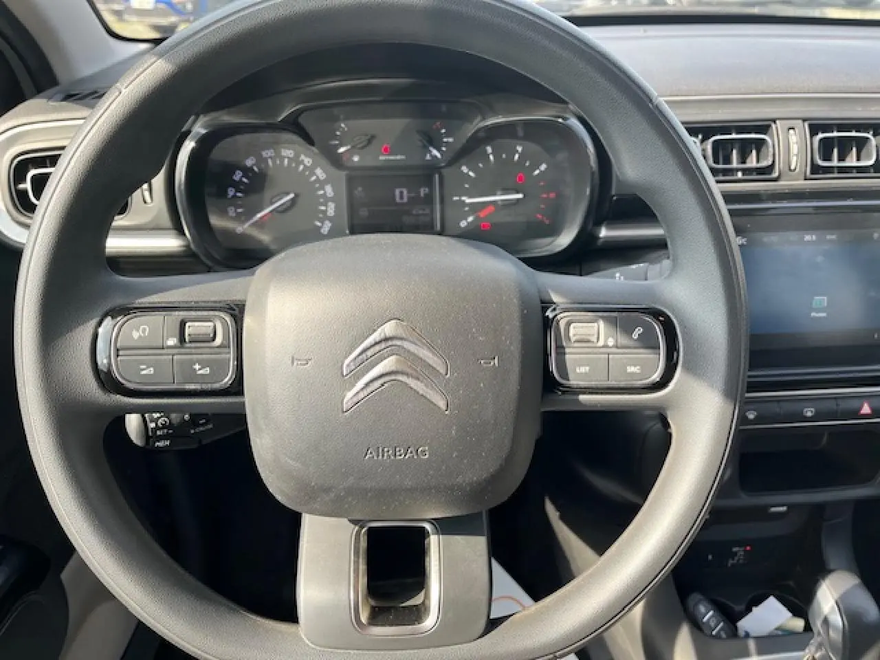 Vue rapprochée du volant noir de la Citroën C3 2023 avec commandes intégrées et tableau de bord numérique.