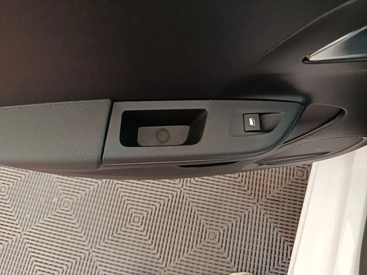 Gros plan sur la poignée intérieure de porte côté conducteur d’une Opel Corsa blanche, avec bouton de verrouillage.