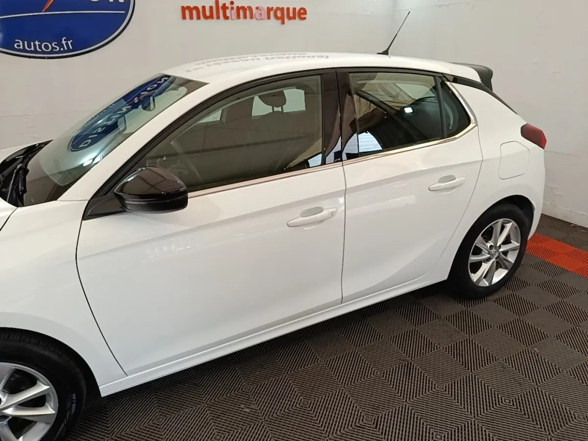 Opel Corsa blanc vue de profil côté gauche, avec rétroviseurs noirs et jantes alliage visibles.