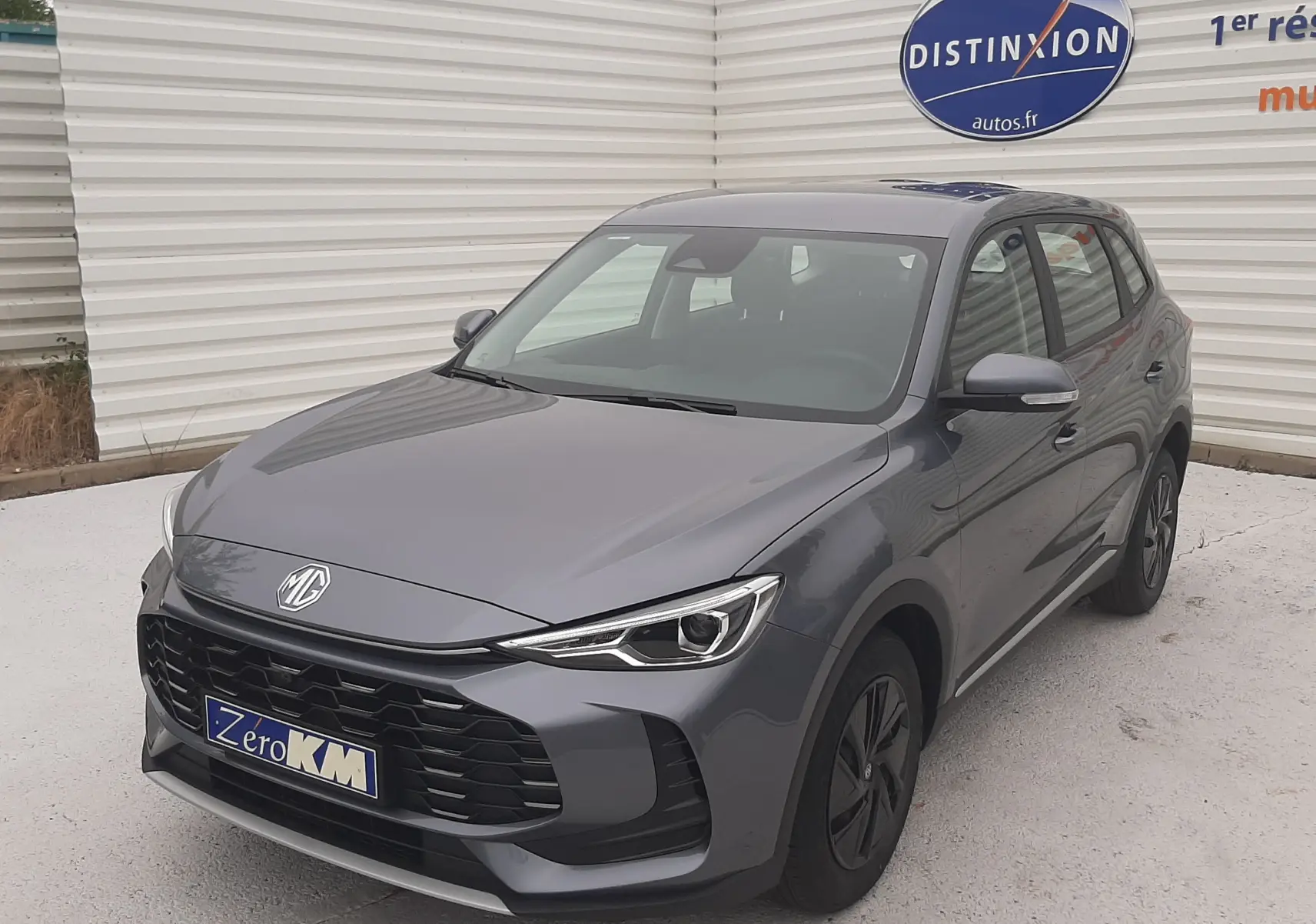 MG Motor ZS 1.5 Hybrid+ gris Camden, vue 3/4 avant droit, avec calandre noire et phares LED fins.