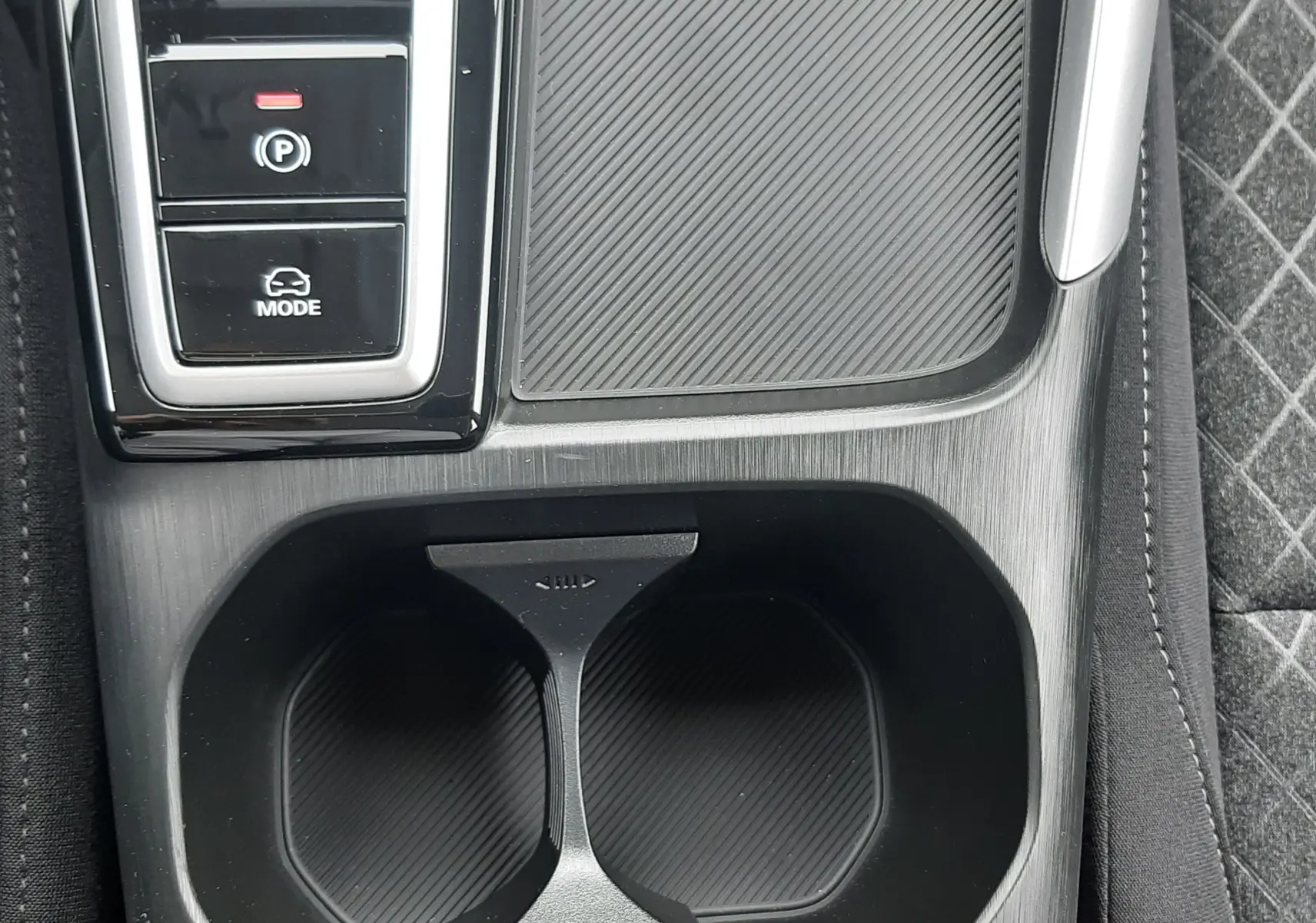 Gros plan sur la console centrale noire du MG ZS 1.5 Hybrid+ 2026, montrant porte-gobelets et commandes de mode de conduite.