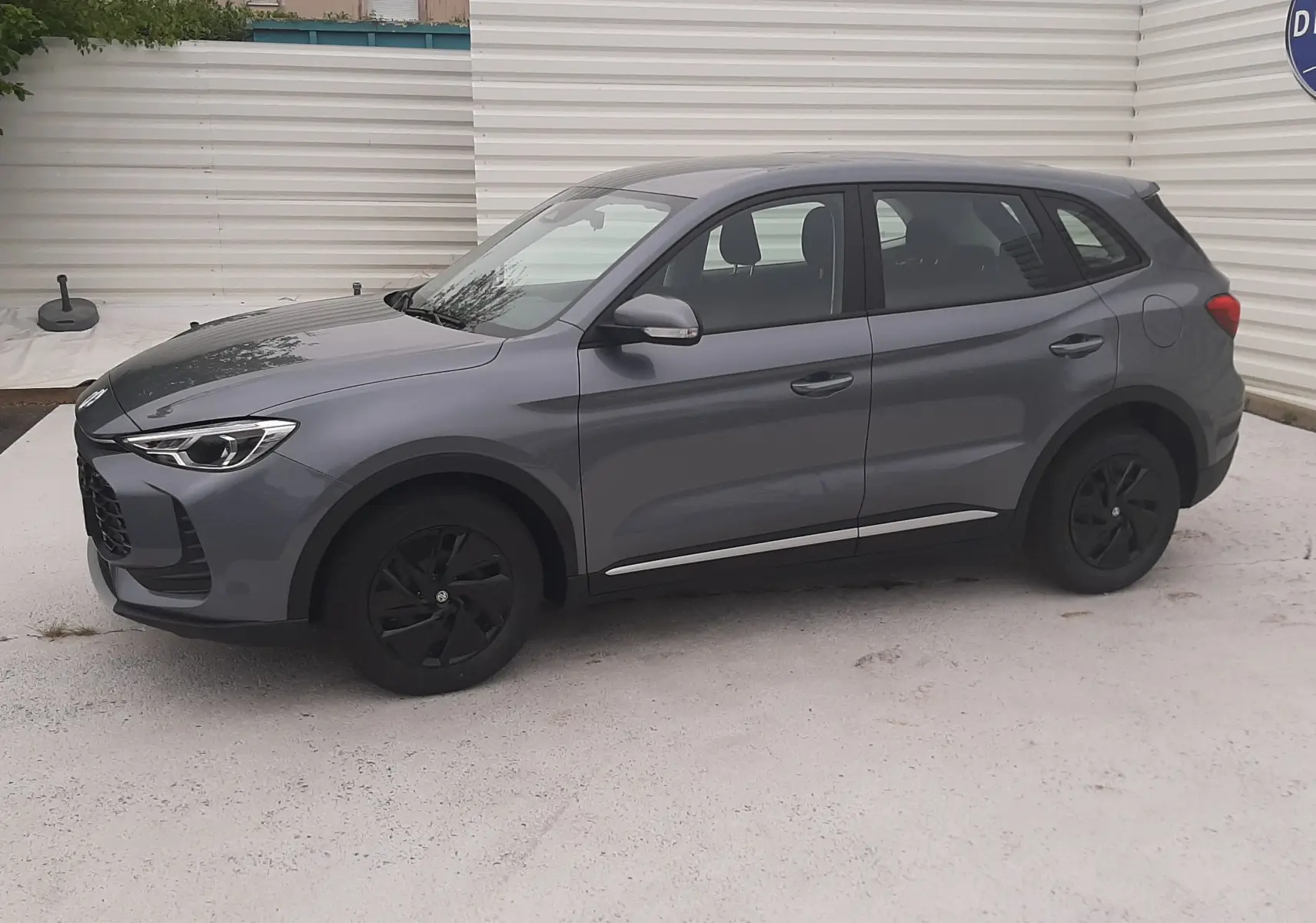 Vue de profil côté gauche du MG ZS 1.5 Hybrid+ 197ch 2026 en gris Camden avec jantes noires et lignes chromées basses.