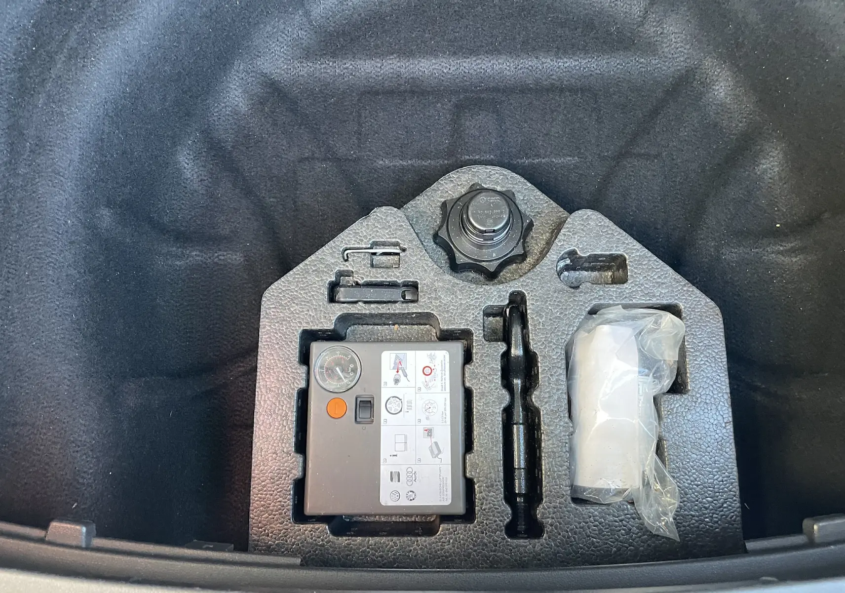 Gros plan sur le kit de réparation de pneu dans le coffre d'une SEAT LEON ST gris 2013, version 1.2 TSI STYLE.