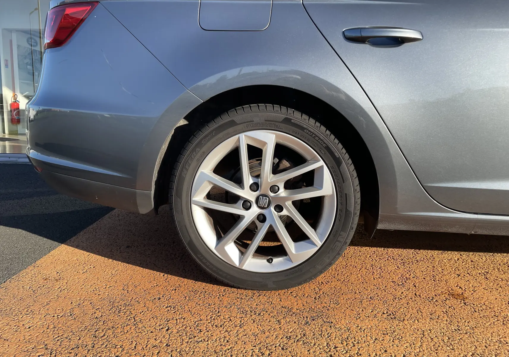 Gros plan sur la roue arrière gauche d'une SEAT LEON ST gris métallisé avec jante alliage à 5 branches doubles.