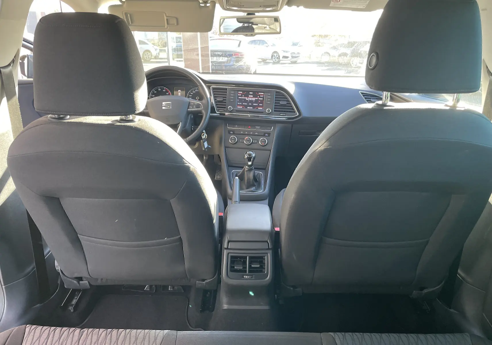 Vue intérieure arrière du SEAT LEON ST gris 2013, montrant les sièges avant en tissu noir et la console centrale avec boîte manuelle.