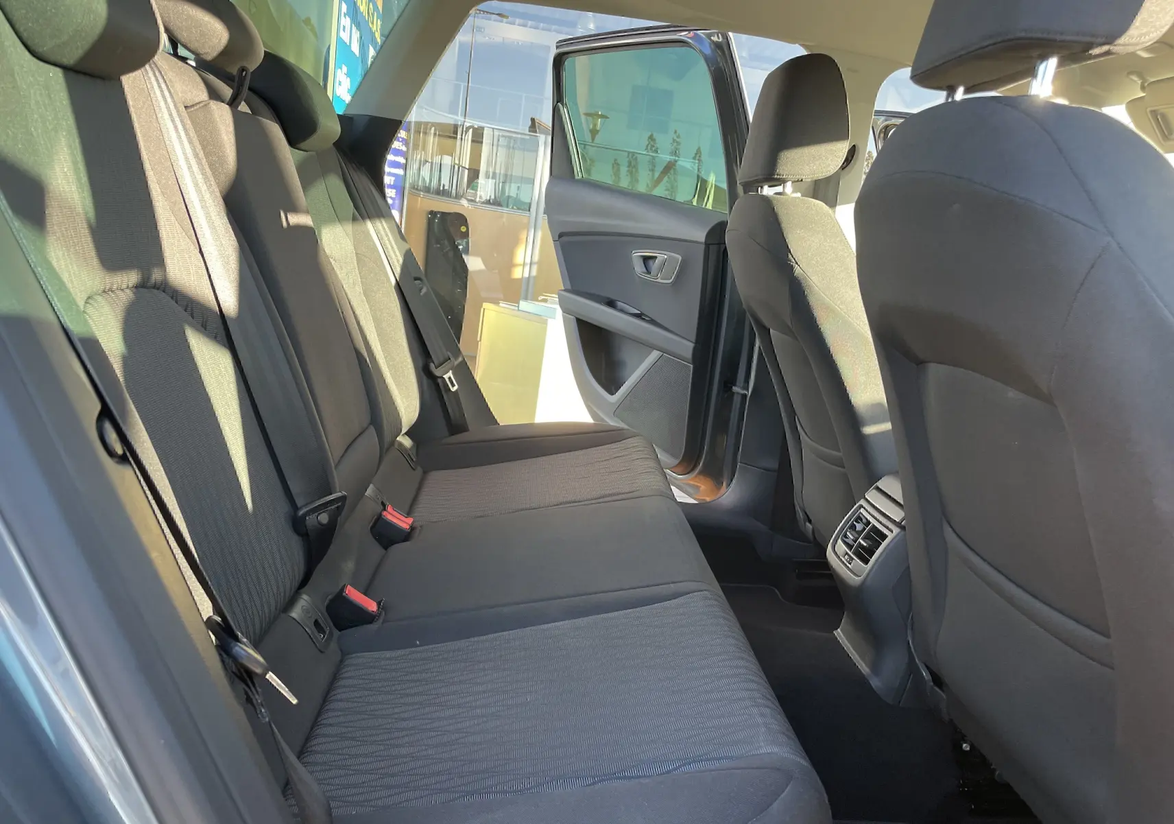 Vue intérieure arrière côté droit d'une SEAT LEON ST gris 2013 avec banquette tissu gris-noir et porte arrière ouverte.