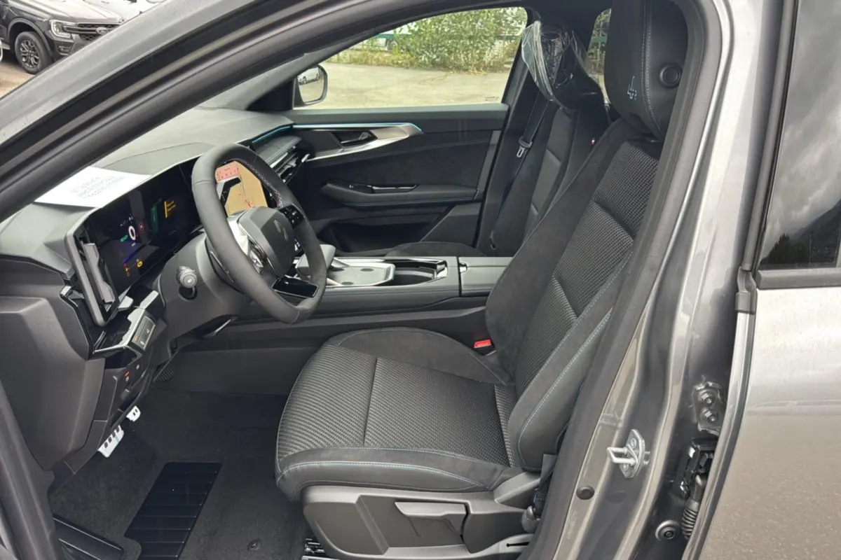 Intérieur avant droit du Renault Austral E-Tech 200 Esprit Alpine Plus 2025, sièges noirs avec surpiqûres bleues et tableau de bord numérique.