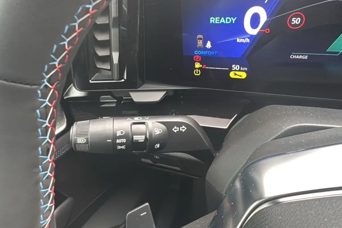 Gros plan sur le commodo gauche et le tableau de bord digital du Renault Austral E-Tech 200 gris schiste avec volant surpiqué tricolore.