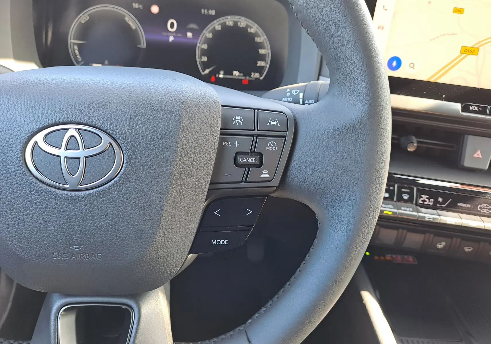 Gros plan sur la manette d'éclairage à gauche du volant du Toyota C-HR gris minéral, tableau de bord numérique visible.