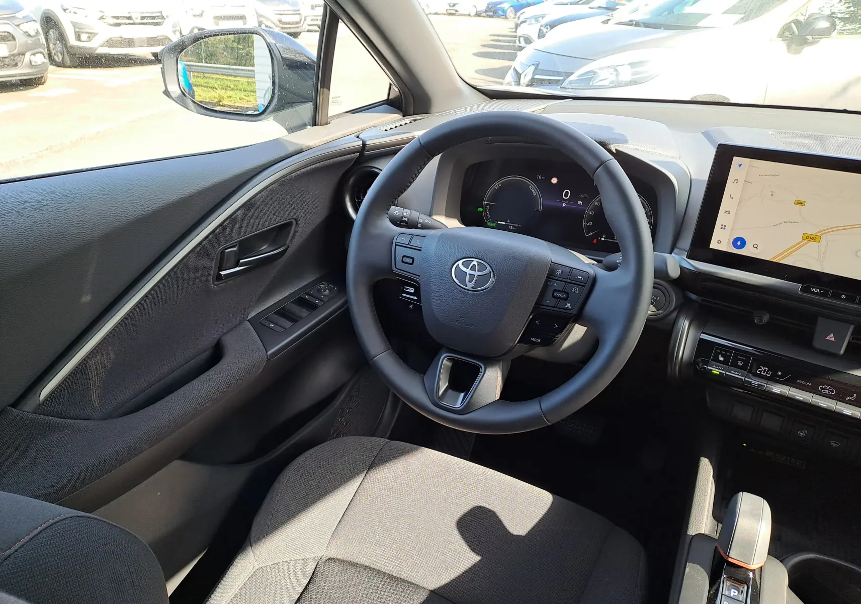 Intérieur côté passager du Toyota C-HR gris minéral 2025 avec écran tactile et aérateurs ronds design.