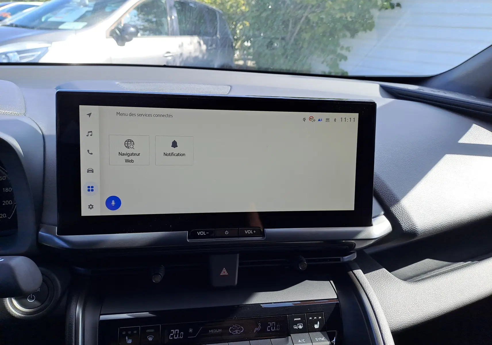 Écran tactile central du tableau de bord du Toyota C-HR gris minéral, affichant le menu multimédia en extérieur lumineux.