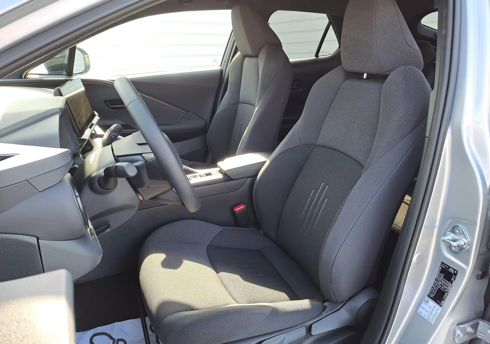 Panneau intérieur côté gauche de porte avant du Toyota C-HR gris minéral, avec commandes de vitres et poignée noire.