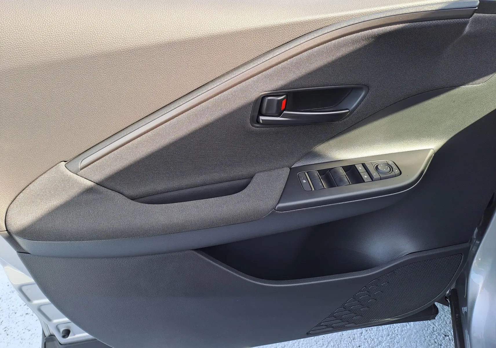 Vue intérieure arrière droite du Toyota C-HR gris minéral 2025, montrant les sièges arrière et le dossier des sièges avant en tissu noir.