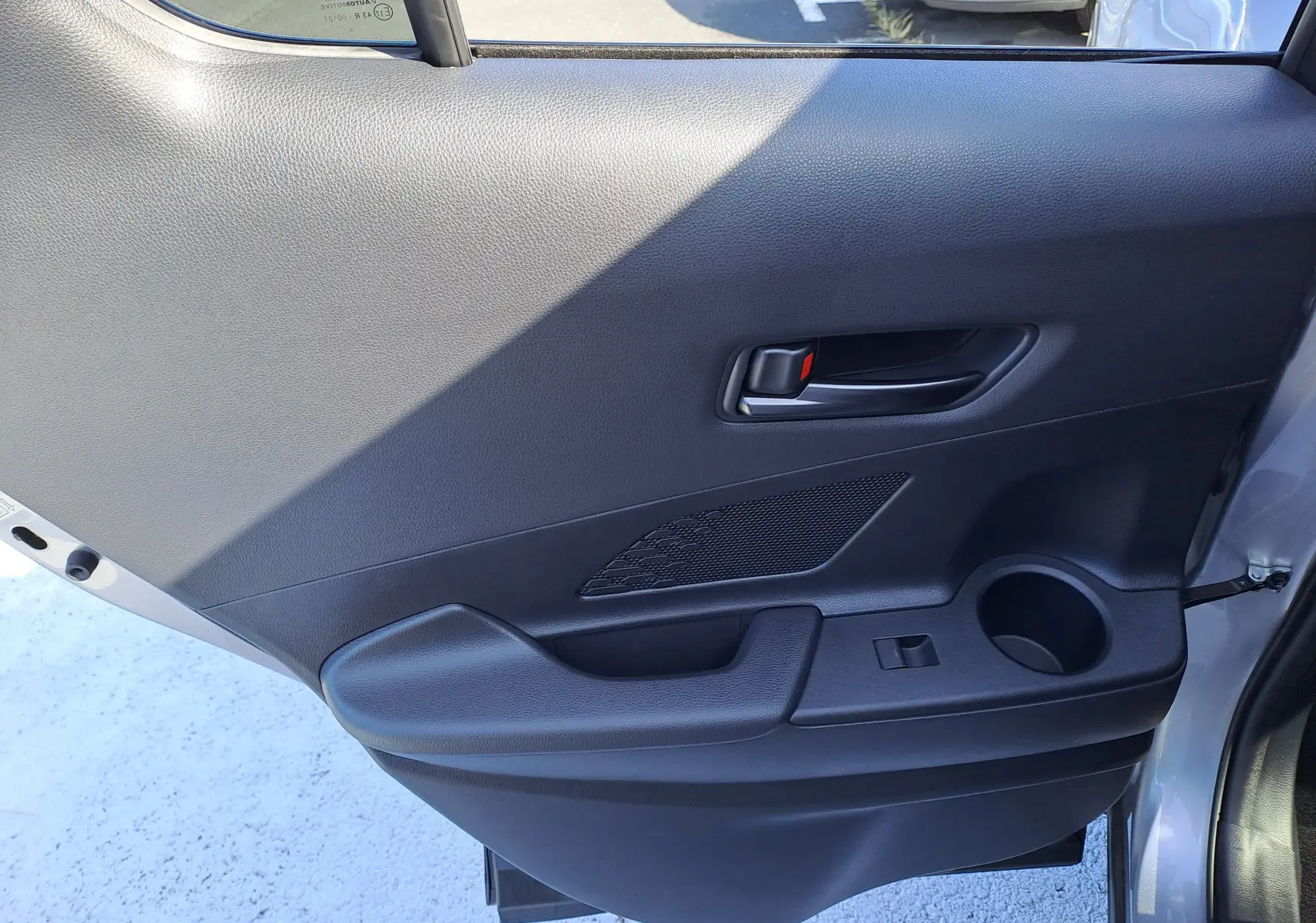 Coffre ouvert d'un Toyota C-HR gris minéral 2025, montrant un espace de rangement propre avec sac Toyota noir.