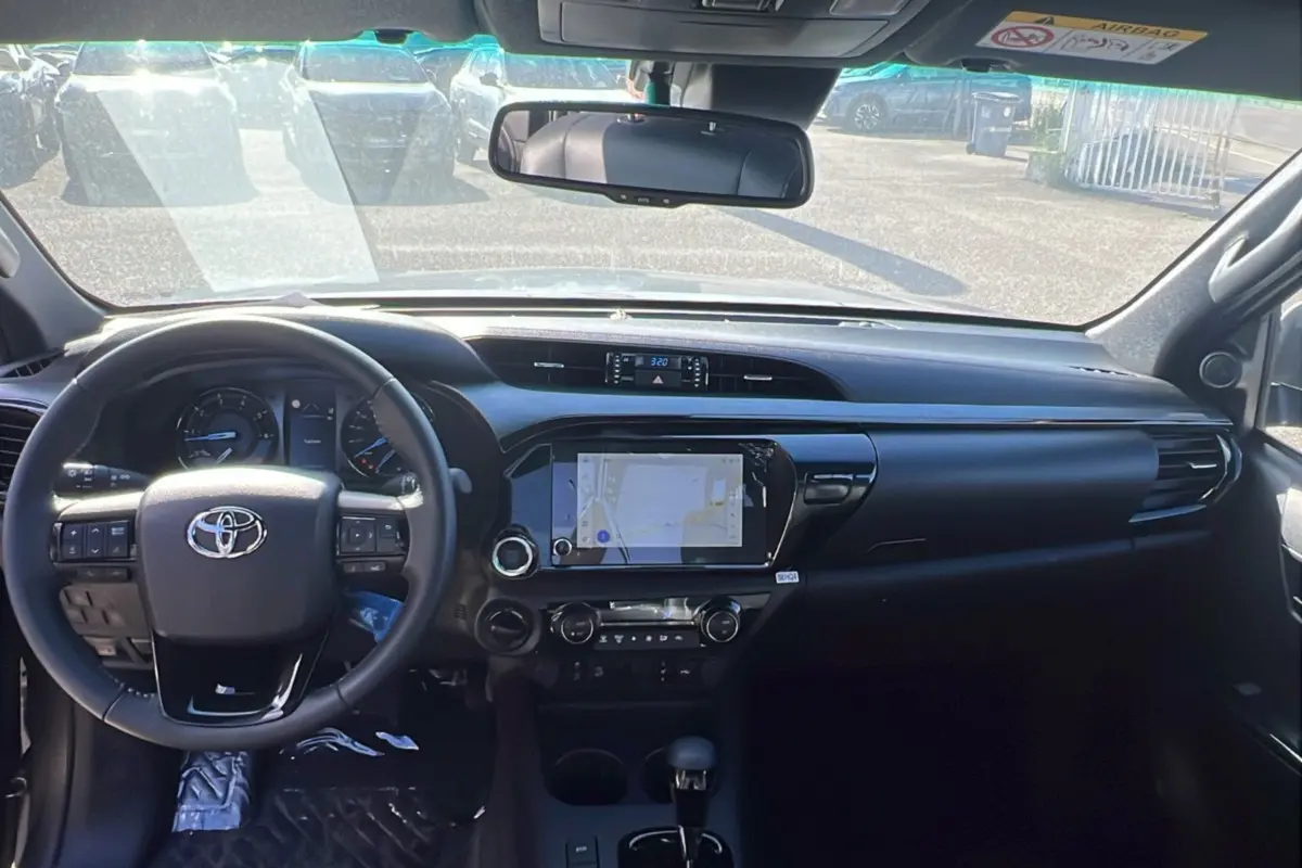 Vue intérieure avant du Toyota Hilux 2025 gris atlas, mettant en valeur le tableau de bord et l'écran tactile central.