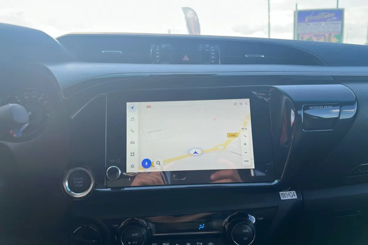 Tableau de bord du Toyota Hilux 2025 avec écran tactile GPS et bouton start/stop, finition Invincible gris atlas.