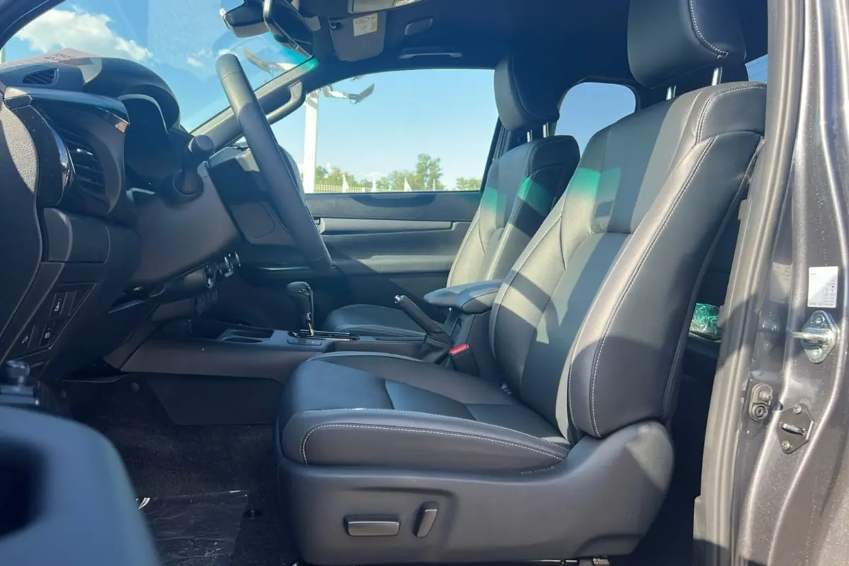 Intérieur du Toyota Hilux Invincible 2025, vue côté conducteur, sièges en cuir noir et tableau de bord moderne.