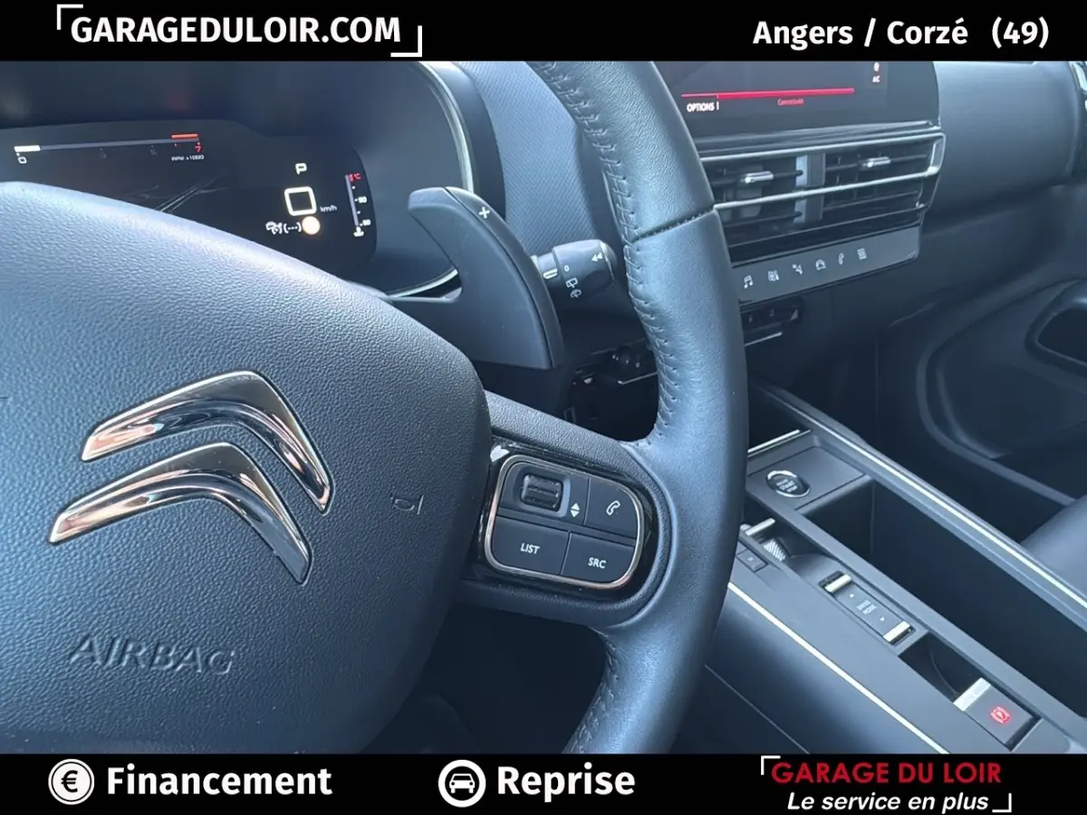 Vue rapprochée du volant cuir noir et de la console centrale du Citroën C5 Aircross 2025, avec commandes multifonctions visibles.