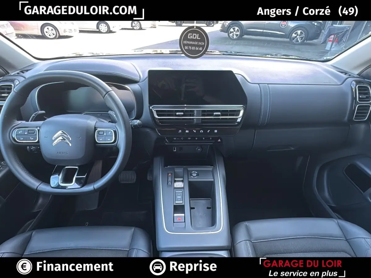 Vue intérieure avant du Citroën C5 Aircross noir, tableau de bord moderne avec écran tactile central et volant cuir.