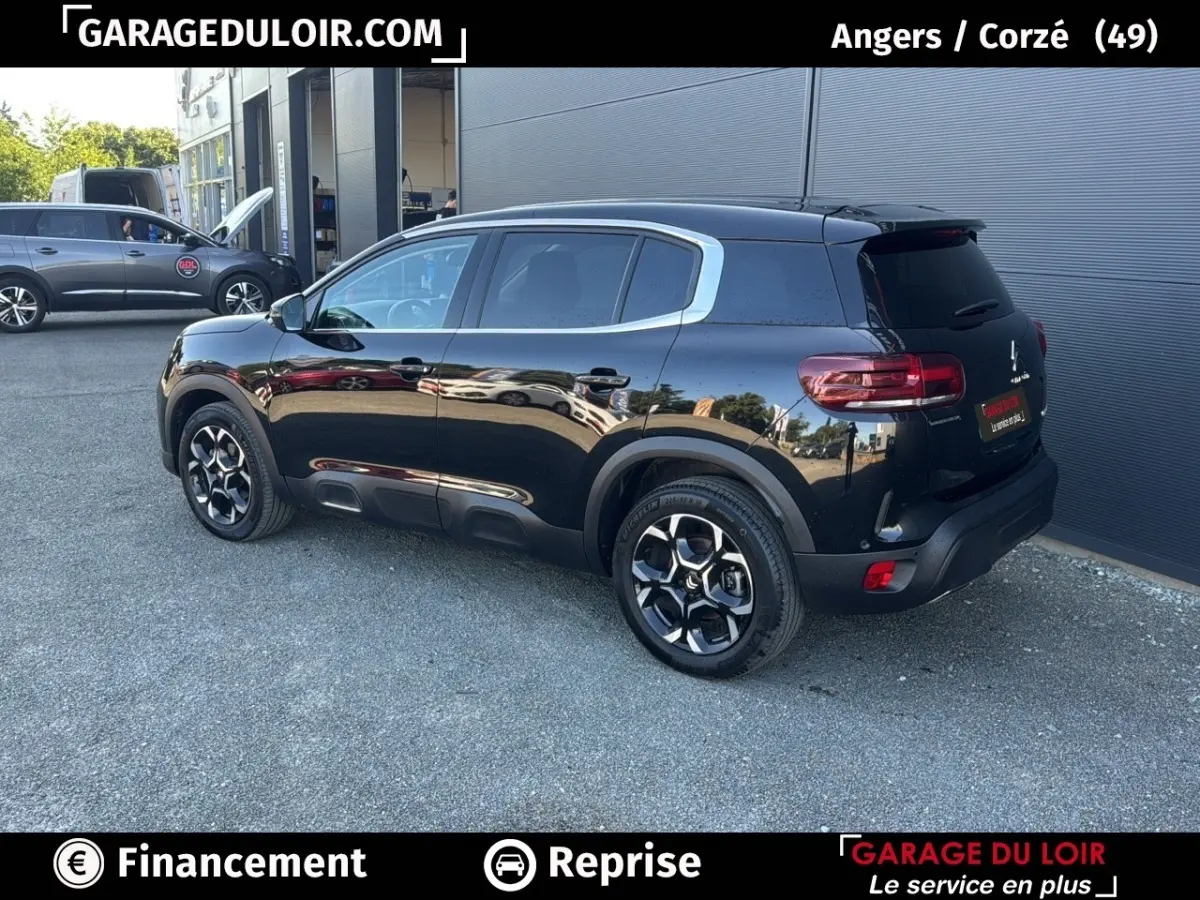 Vue 3/4 arrière droite d'un Citroën C5 Aircross noir brillant avec jantes alliage et vitres teintées.