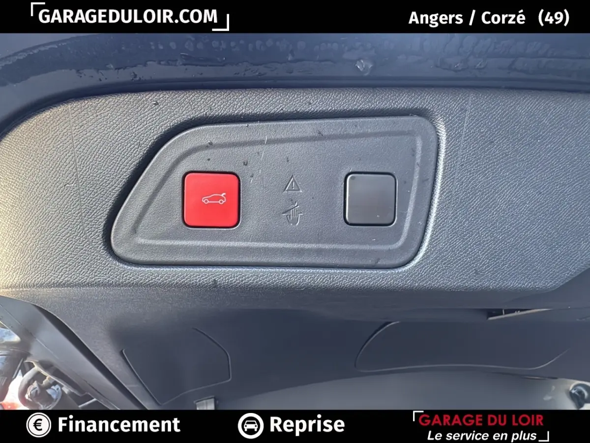 Gros plan sur le bouton rouge d'ouverture du coffre dans le hayon noir du Citroën C5 Aircross 2025.