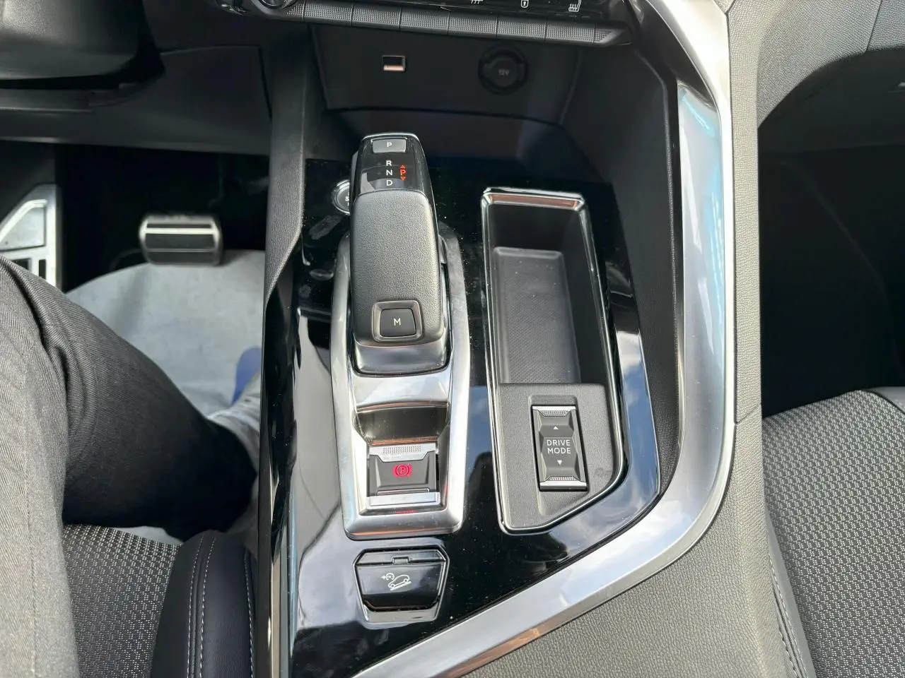 Vue plongeante sur la console centrale noire brillante du Peugeot 3008 2024, avec levier de vitesses automatique et bouton Drive Mode.