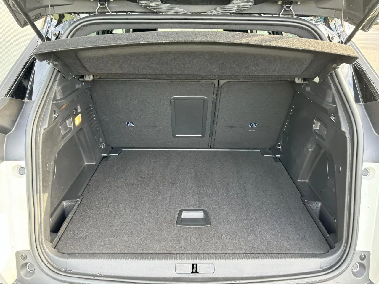 Coffre ouvert vu de l'arrière d'un Peugeot 3008 blanc nacré, montrant un espace de chargement propre et spacieux.
