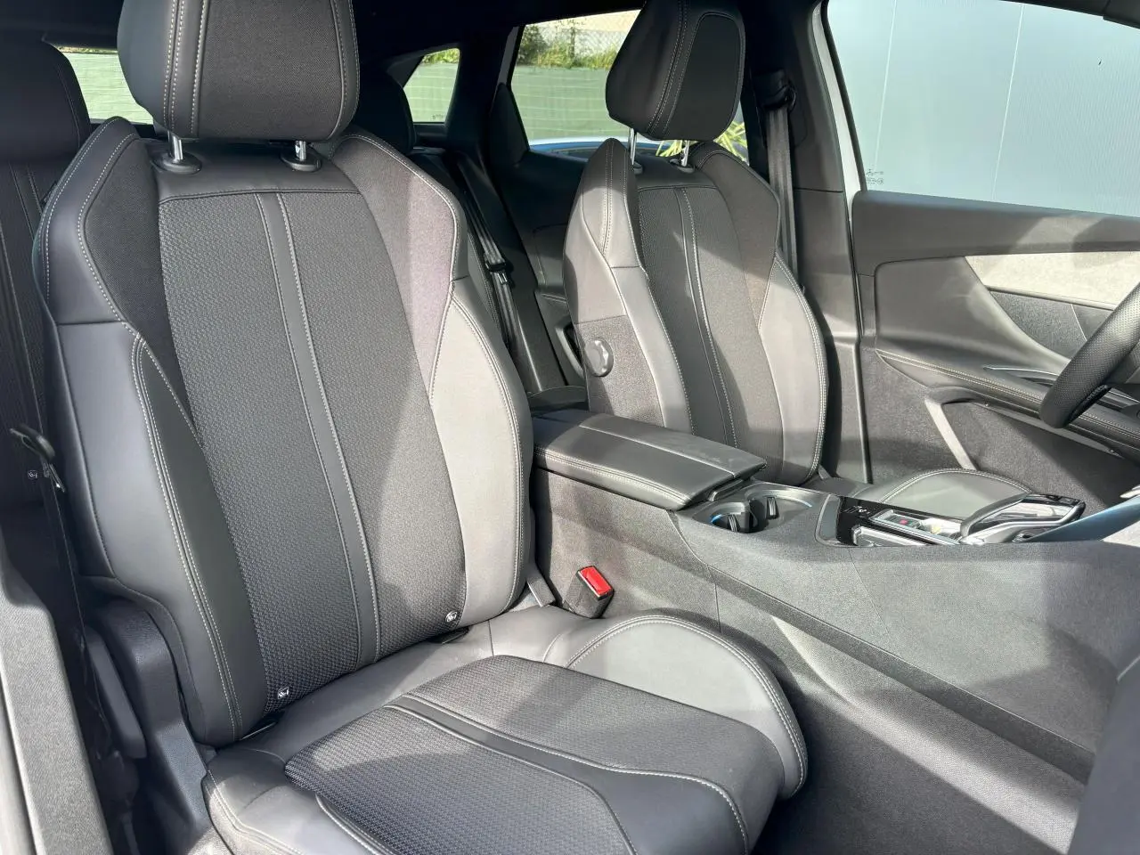 Vue intérieure sur les sièges avant en sellerie Mi-TEP/tissu gris foncé du Peugeot 3008 2024, avec accoudoir central.