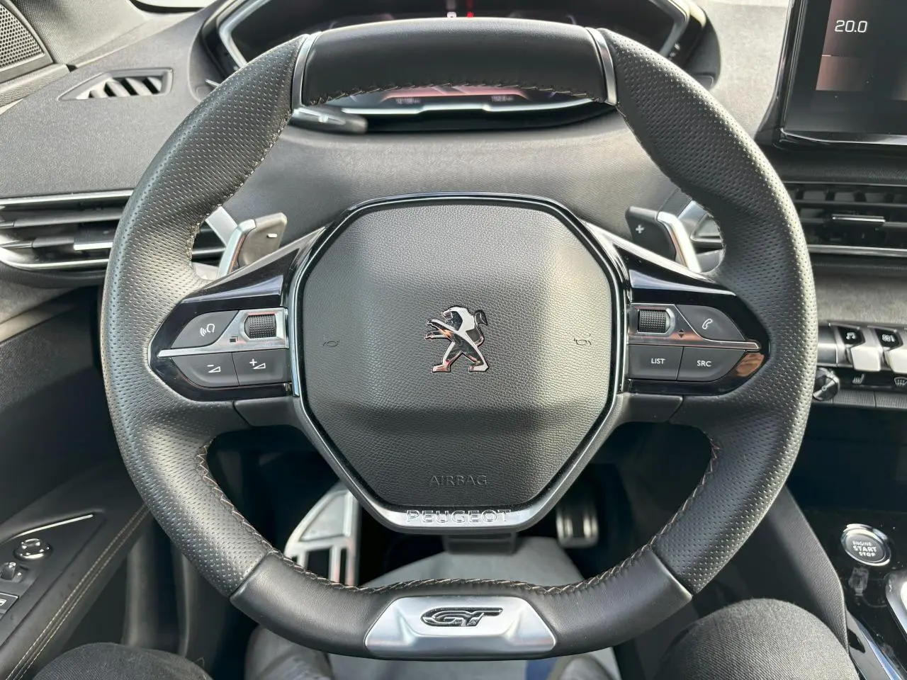 Vue rapprochée du volant cuir perforé noir avec badge GT et commandes multifonctions du Peugeot 3008 2024.