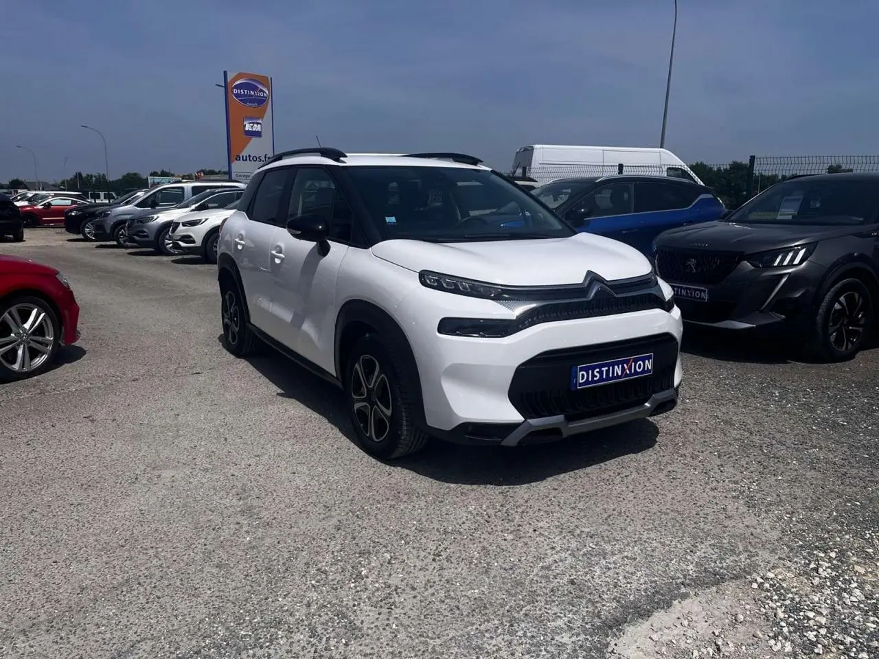 Citroën C3 Aircross blanc banquise vue 3/4 avant droit avec barres de toit noir brillant sur parking.