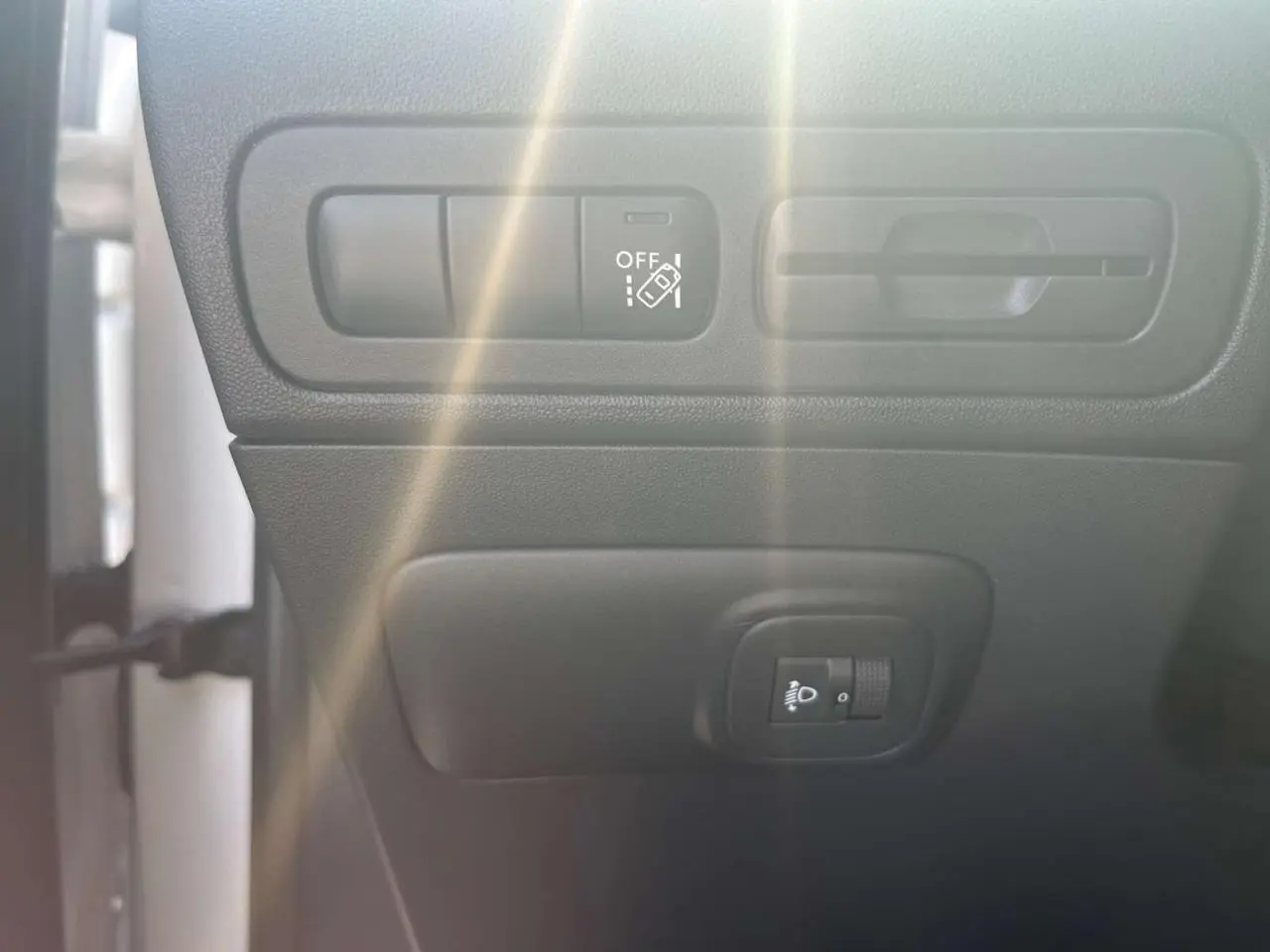 Détail des commandes d'assistance et réglage des phares dans l'habitacle d'une Citroën C3 Aircross blanc banquise.