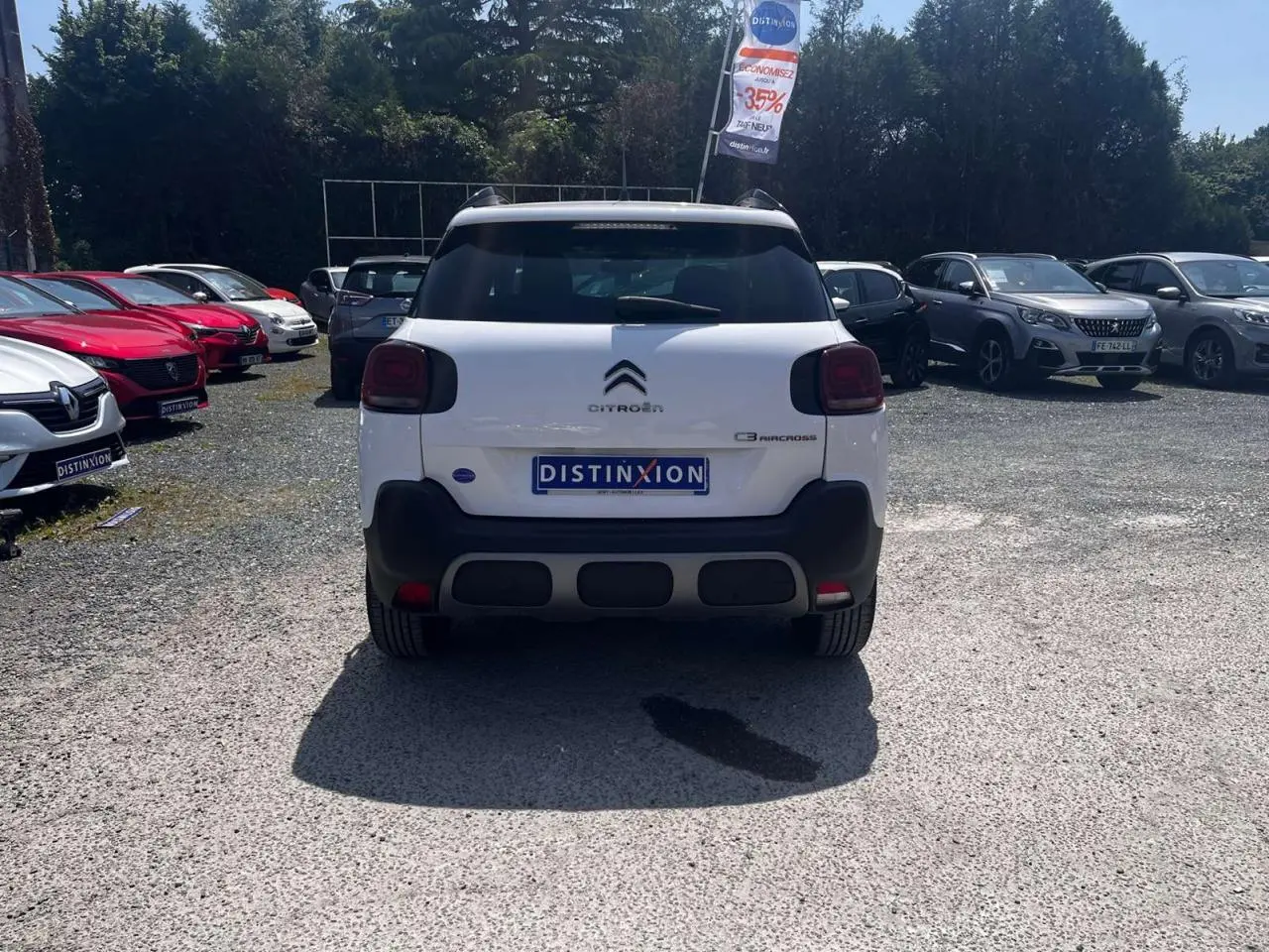 Vue arrière d'un Citroën C3 Aircross blanc banquise avec barres de toit noir brillant sur un parking extérieur.