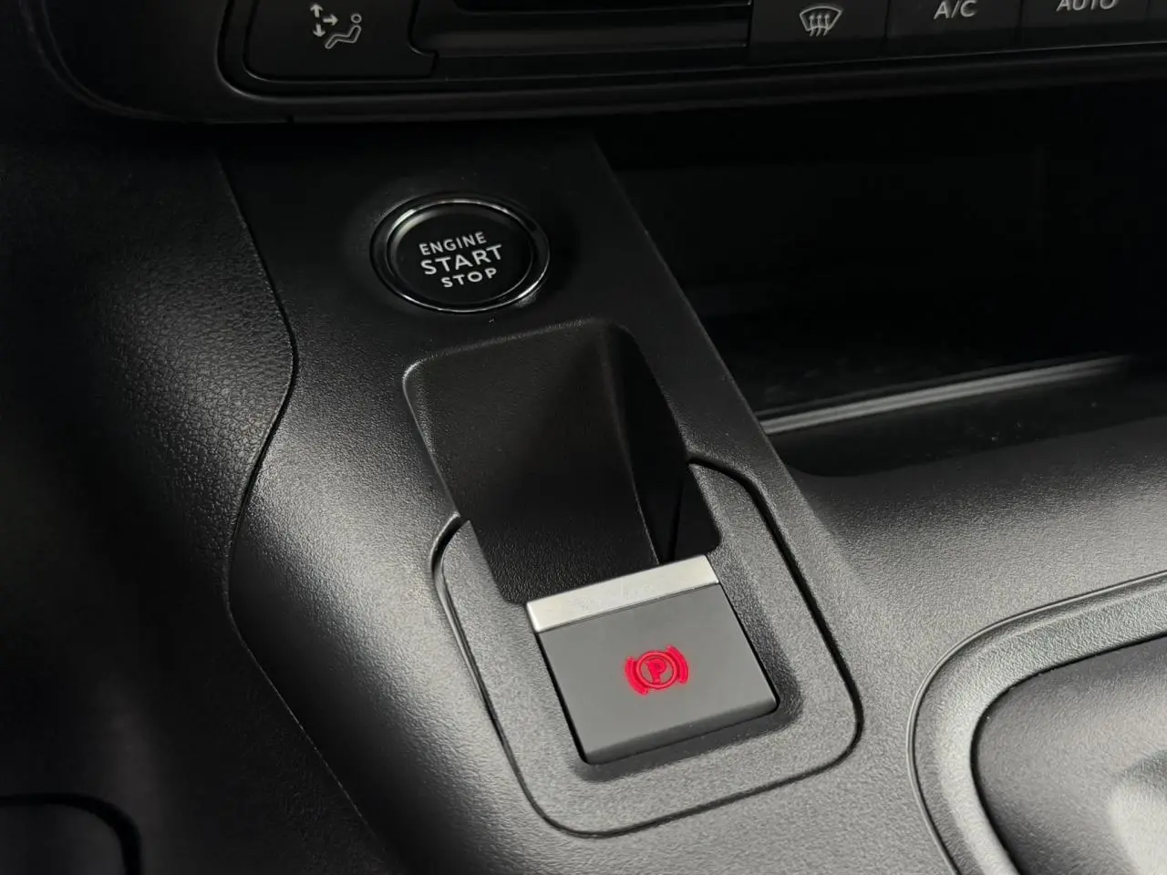 Gros plan sur la console centrale du Peugeot Rifter gris, avec bouton de démarrage et frein de stationnement électrique.