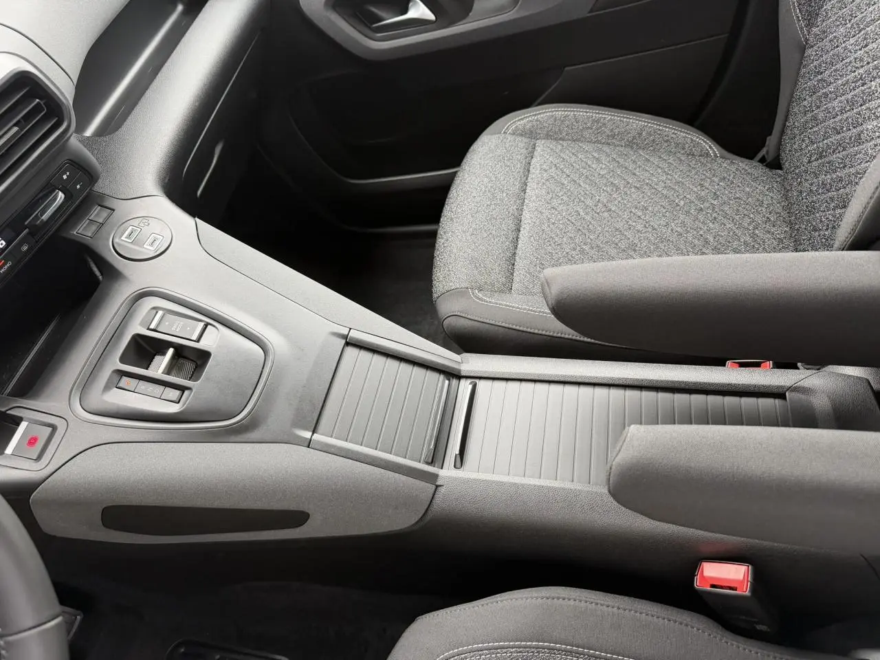 Vue intérieure centrée sur la console centrale et sièges avant gris du Peugeot Rifter 2026, version Allure.